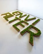 Napis z nazwą firmy z mchu stabilizowanego na drewnie.