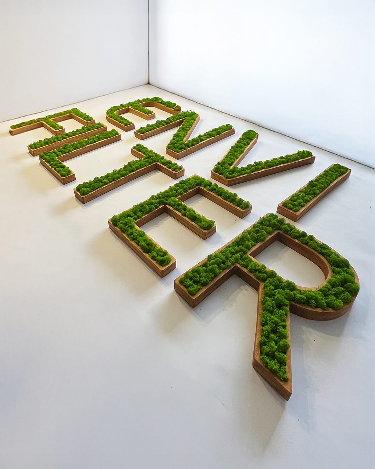 Napis z nazwą firmy z mchu stabilizowanego na drewnie.