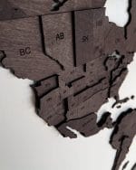 Mapa świata 3D w kolorze czekolady Drewniana mapa świata 3D w kolorze czekolady zawieszona na białej ścianie.